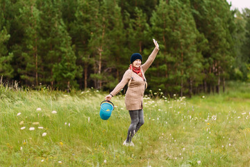 Fototapeta premium cheerful happy fifty-year-old woman collects mushrooms in a bucket in the forest