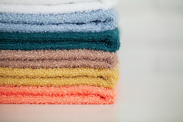 Colorful cotton towels in bathroom on white wooden table