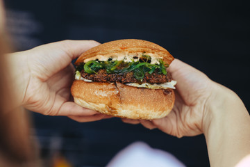 tasty burger. stylish hipster woman holding juicy hamburger in hands close up.