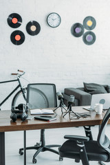 furnished broadcasting studio with microphones, laptop and headphones on wooden table