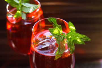 Close up of red cocktail with ice cubes green mint leaves in wine glass