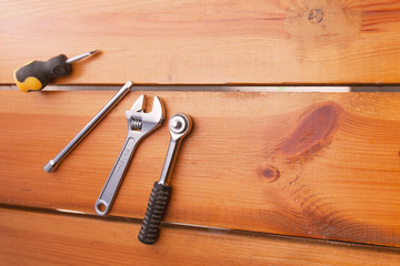 A various assortment of tools is laying on a wooden surface