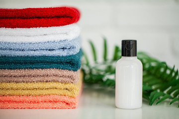 Cosmetic products and cotton towels on white wooden table in beauty salon