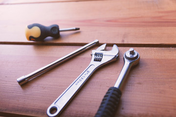 A various assortment of tools is laying on a wooden surface