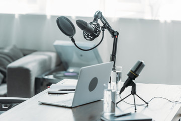 workplace with microphones, laptop, notebooks and glasses with water in broadcasting studio
