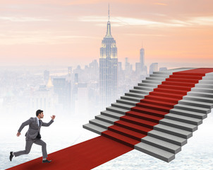 Fototapeta na wymiar Young businessman climbing stairs and red carpet