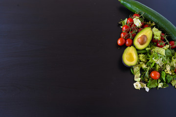 tomatoes, avocado and cucumber on the black background