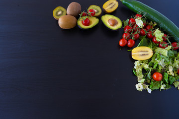 kiwi, lettuce, tomatoes, avocado and cucumber on the black background