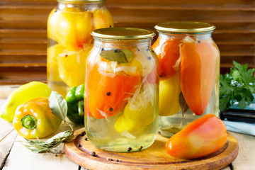 Homemade preserving. Bulgarian Pepper stuffed with vegetables in marinade on the kitchen wooden background.