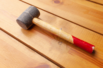 A black mallet is laying on a wooden surface