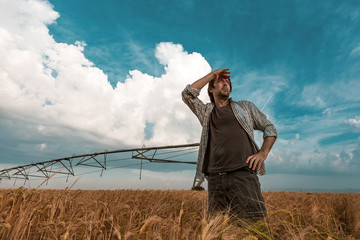 Worried farmer in barley field on a windy day