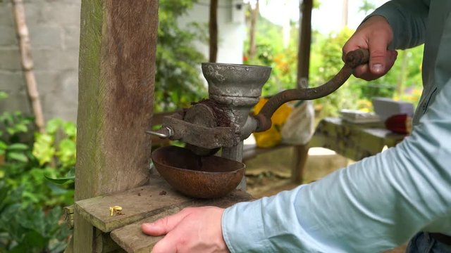 A man grinding cocoa beans with hand mill outdoors in Cuba in 4k