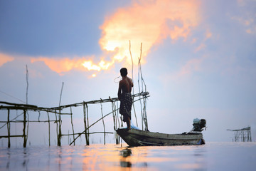 Fishermen on boat fishing with a large fishnet.Silhouette scene of the morning.