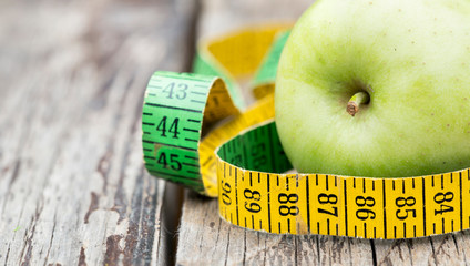 Web banner of weight loss, diet concept - green apple with tape measure on a wooden background with...