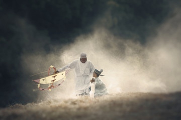 Father with his son playing with kite.Scene of morning with the mist and soft focus. Muslim Family Vacation.