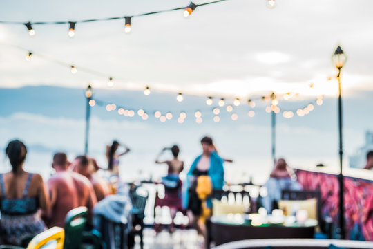 Defocused People Attending Open Air Summer Party On The Roof Top. Warm Sun Light In The Evening.