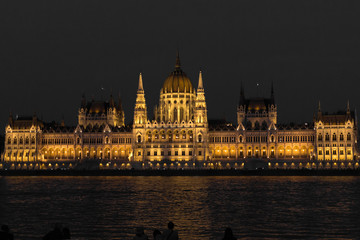 Fototapeta na wymiar Parliament Building in Budapest. State institution in Hungary. Exterior of a historic building. Coats of arms on the wall. Statue with horses on the roof of the parliament. European architecture.