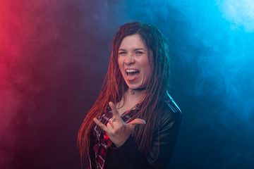 Fototapeta premium Youth, hairstyle and modern concept - young woman with dreadlocks smiling over the red and blue light background