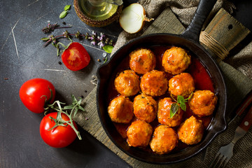 Homemade Meatballs with spices and tomato sauce in a frying pan on dark stone table. Flat lay, top view background.
