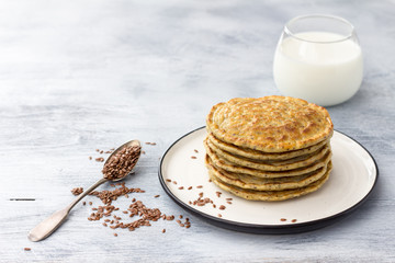 Vegan pancakes with flax seeds and vegan milk on a white plate on a gray background, free space. delicious homemade healthy food