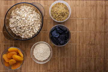 oat flakes with dried apricots  seeds flax and sesame and prunes stand on a wooden tray 
