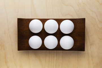 white chicken eggs are  on a wooden stand