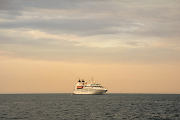 Naklejka premium Seascape with a cruise ship on the horizon and cloudy sunset sky, Portofino, Genoa, Liguria, Italy