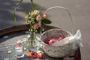 Dekoration mit Blumen, Kerze und Körbchen auf Fass