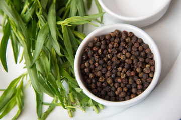 Black pepper in white bowl over white background . Saucer dish with black pepper peas isolated on white background . Dry black peppers isolated with path .