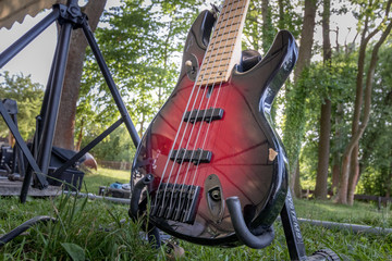 Elektro-Gitarre, rot schwarz auf Ständer im Grünen, outdoor