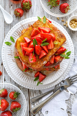 French toasts, French toasts made of sliced brioche with fresh strawberries, mint and honey, top view.  Delicious breakfast or dessert