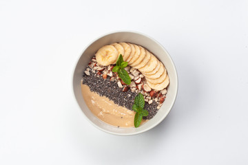 Sweet oatmeal breakfast bowl with porridge, honey, chia seeds, chopped nuts and banana slices, isolated on white background