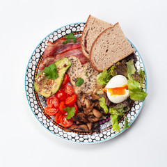 Big breakfast keto bowl: avocado with hazelnut, roasted chicken breast, rye bread toasts, mixed salad, tomato, hard boiled egg and champignon isolated on white background