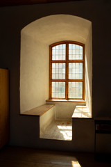 An arched window opening in an old castle and benches made by the window from thick walls, authentic interior of the medieval historic Abo castle in the city of Turku in Finland on a sunny day.