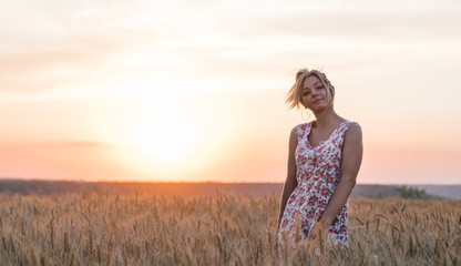 Obraz premium young seductive rural blond hair woman in dress on the yellow wheat field on the sunset, lake on the background