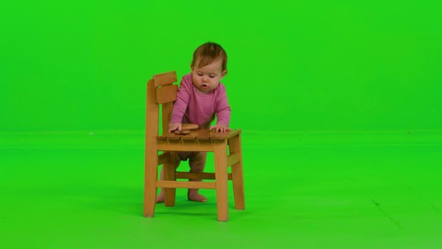 Playing happily with wooden toys by a beautiful baby girl over a green screen.