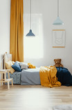 Teddy bear on single wooden bed in blue and orange bedroom interior