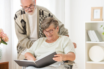 Happy Senior married couple with photo album at nursing home