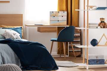 Workspace with desk and chair in elegant teenager's room with blue and orange design