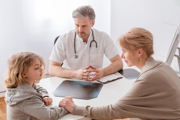 Mom and cute sick son in front of the handsome pediatrician's desk