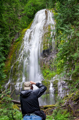 Photographer shooting waterfall in forest,  Oregon, USA