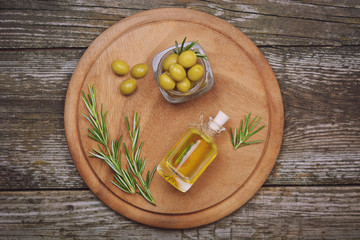 Olive oil and green olives in bowl on wooden board over wooden background, top view. Greek oil and olives concept