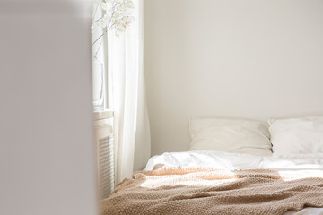 Closeup of comfortable bed with white linen bedding and beige warm blanket, real photo with copy...