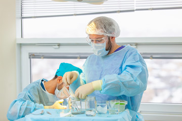 Baldness treatment. Hair transplant. Surgeons in the operating room carry out hair transplant...