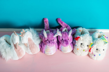 Variety of cute soft 3d llama, dragon and swan slippers on the pink and blue background