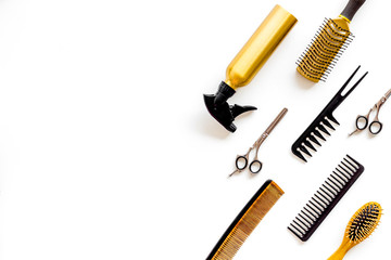 professional accessories of hairdresser with combs and spray on work desk white background top view copyspace