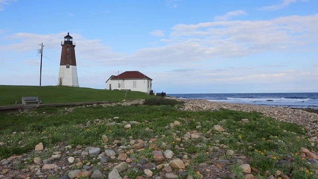 Tilt up reveals historic Point Judith Lighthouse on rocky beach in Rhode Island