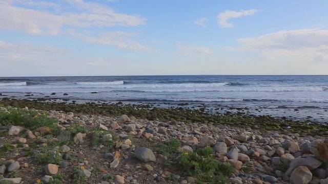 Scenic panning shot reveals stone piles on beach at Point Judith, Rhode Island