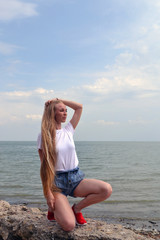 Fototapeta na wymiar Young woman in white t-shirt relaxing by the sea