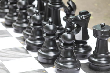 giant black and white chess figures on a chessboard